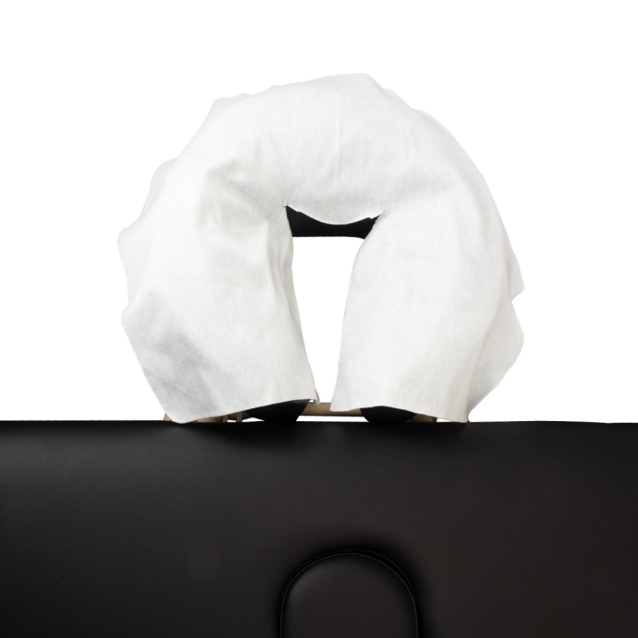 Une housse d’Appui-Tête Jetable – Non Fixe (pack de 100), blanche et jetable, est placée sur l’appui-tête d’une table de massage noire.